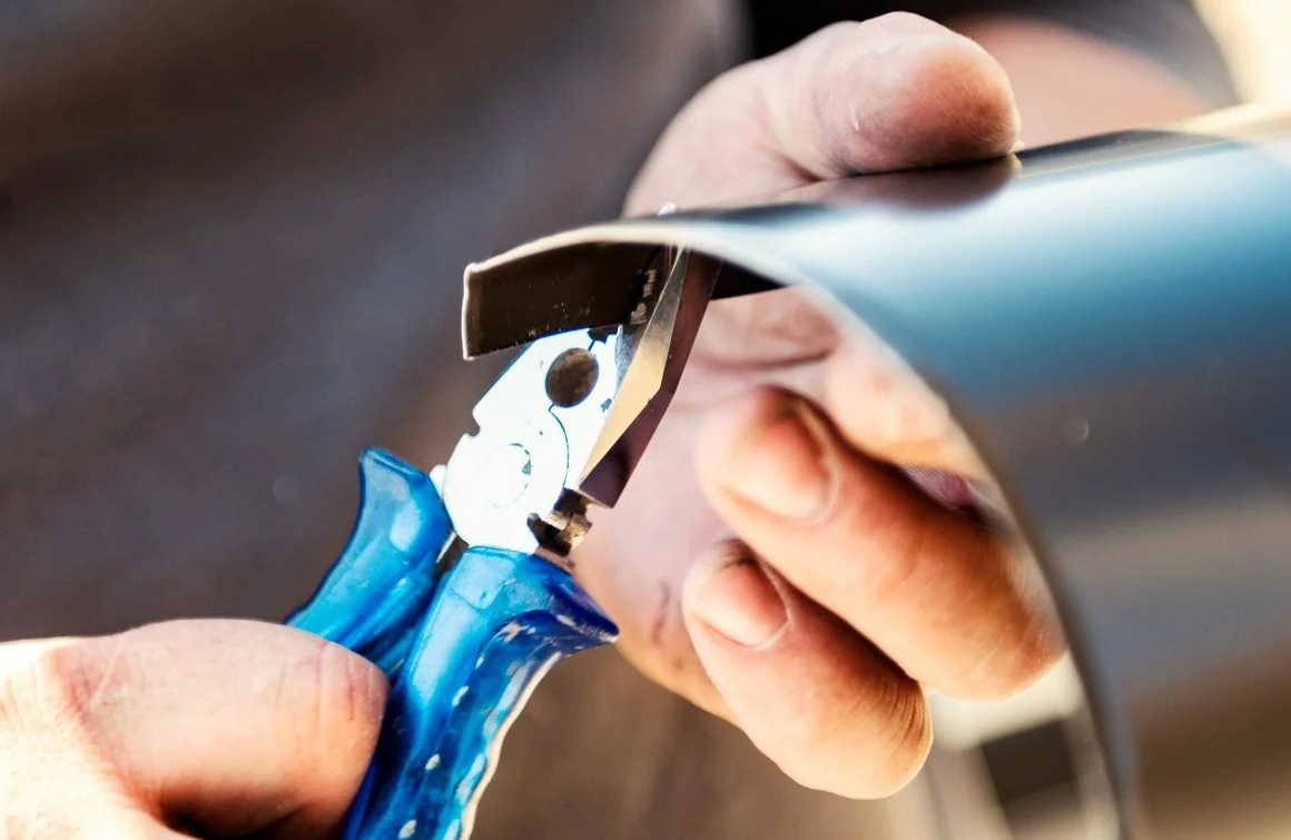 Hand biegt Blech mit Zange